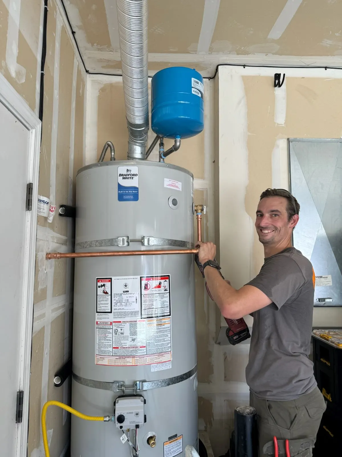 HOTCO technician installing a new gas tank water heater with expansion tank in a Roseville, CA garage - Water Heater Replacement